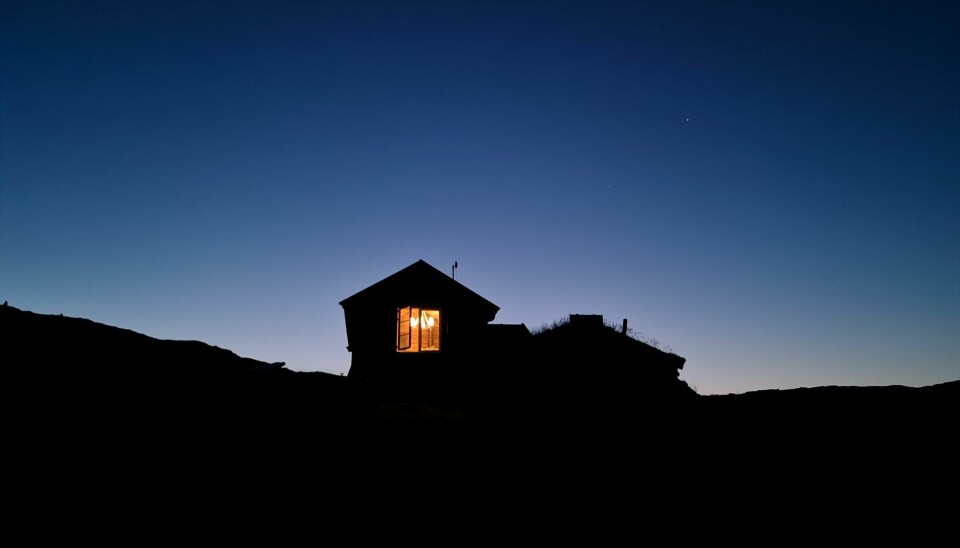 Hytte på fjellet. Nattehimmel. Lys i vinduet.