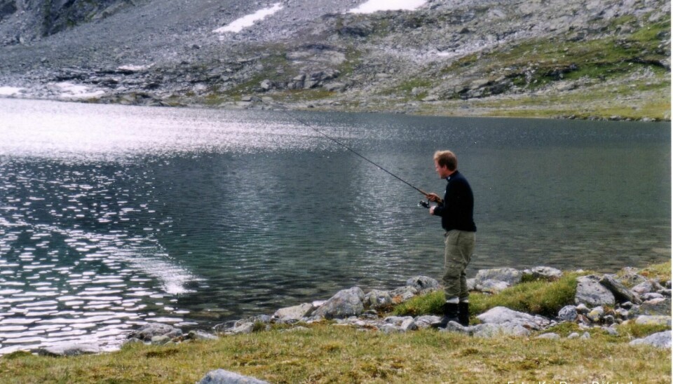 Mann fisker med stang etter fjellørret i Skurveosen, Dalsida statsalmenning, Lesja kommune.