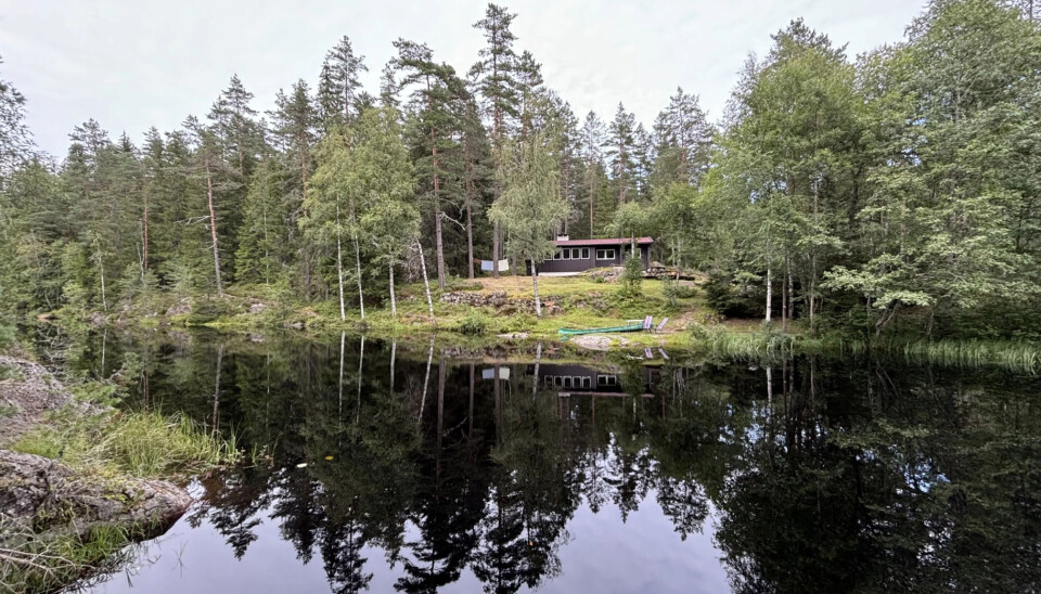 Hytta ligger idyllisk ved vannkanten.